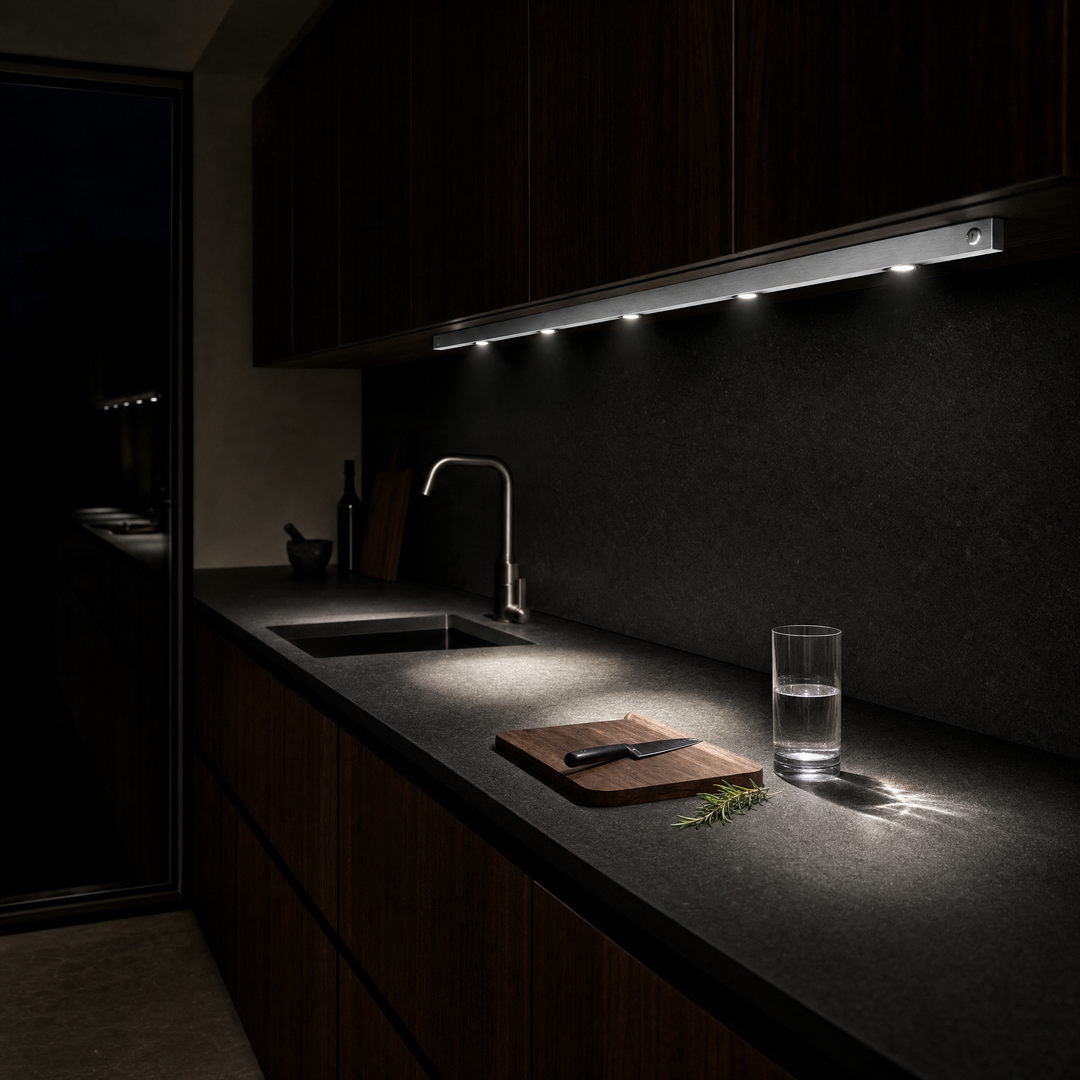 A dark modern kitchen at night lit only by the Ambient Sensor Light under the wall cabinets
