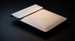 VELA laptop sleeve lit against a dark charcoal background, showing its slim profile