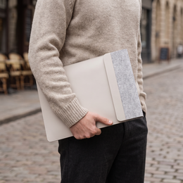 Person carrying the closed VELA laptop sleeve under one arm on a city street