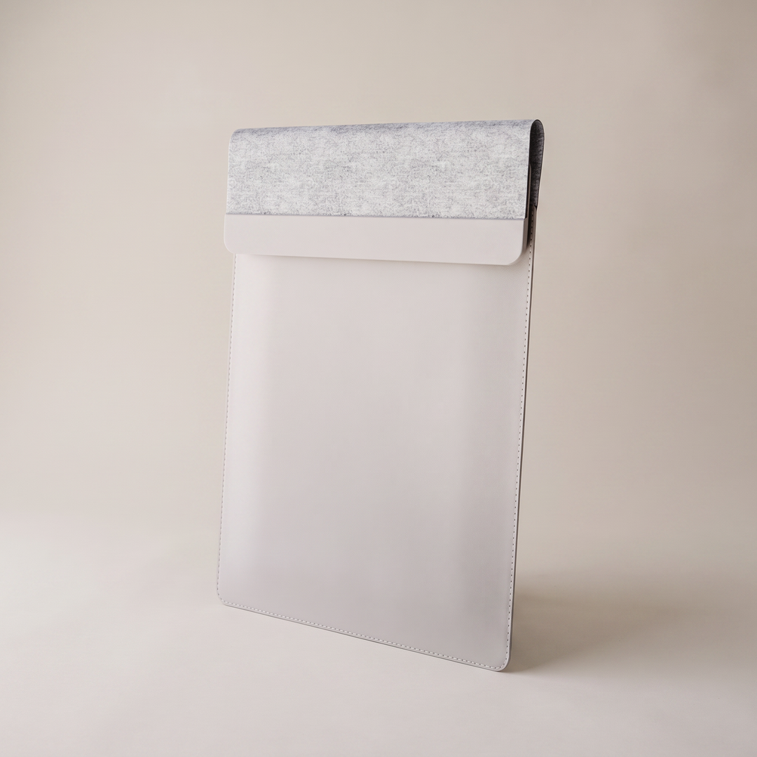 VELA laptop sleeve in light grey with a felt band, standing upright on a neutral studio backdrop