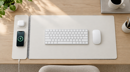 VoltDesk on an oak desk with keyboard and mouse, phone and earbuds charging on the panel alongside