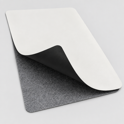 The VoltDesk leather sheet curled back to show it is white on one side and black on the other, over the grey felt base