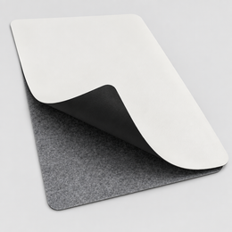 The VoltDesk leather sheet curled back to show it is white on one side and black on the other, over the grey felt base